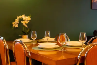 a wooden table with plates and wine glasses on it at Tauron Arena Homely Apartment by BookingHost in Kraków