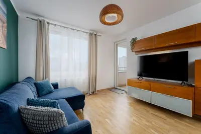 a living room with a blue couch and a flat screen tv at Tauron Arena Homely Apartment by BookingHost in Kraków