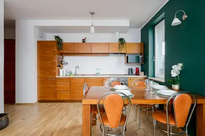 a kitchen with a wooden table and chairs at Tauron Arena Homely Apartment by BookingHost in Kraków