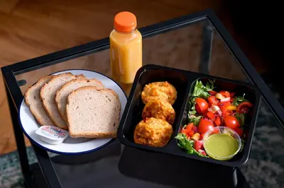 a lunch box with a plate of food and bread and vegetables at Native Apartments Sarego 16 in Kraków