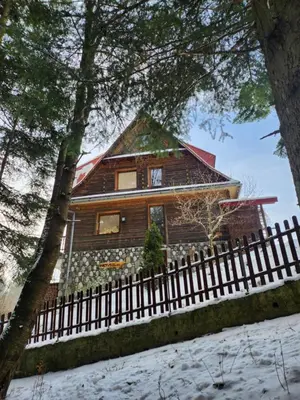 a wooden house with a fence in the snow at Uroczysko pod Babią Górą in Zawoja