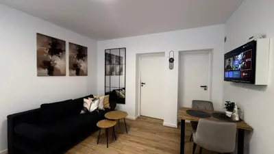 a living room with a black couch and a table at Mickiewicz House Apartamenty in Wadowice