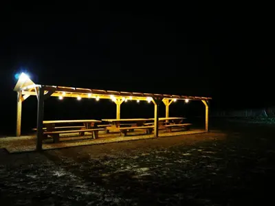 a group of picnic tables with lights at night at Apartament Pod Dębiną