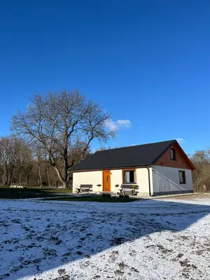 a small white house with a black roof and a field at Apartament Pod Dębiną