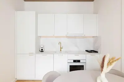 a white kitchen with a table and a sink at Pawlikowskiego 12 by Homeprime in Kraków