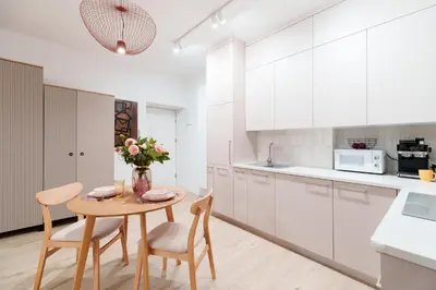 a kitchen with white cabinets and a table and chairs at Cozy & Modern Apartments, Old Town in Kraków