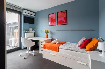 a bedroom with a desk and a bed with orange sheets at Apartament Old Town Comfort Balkon & Parking in Kraków
