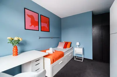 a bedroom with blue walls and a bed with orange sheets at Apartament Old Town Comfort Balkon & Parking in Kraków
