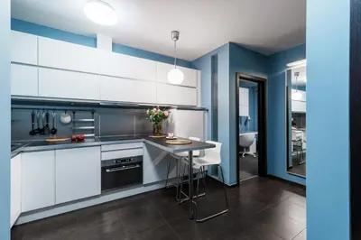 a kitchen with white cabinets and blue walls at Apartament Old Town Comfort Balkon & Parking in Kraków