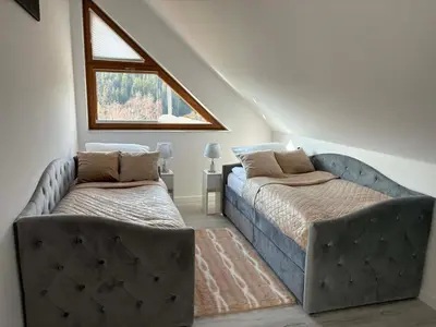 a living room with a couch and a table and chairs at Glamoon Mountain Apartment - Prywatne spa w sercu Podhala in Nowy Targ