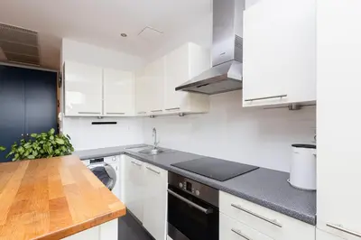 a kitchen with white cabinets and a wooden counter top at Sunny 2B apartment in City Centre in Kraków