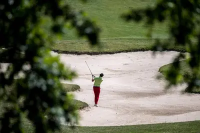 a person standing on a golf course holding a club at Stay at Royal Kraków Golf