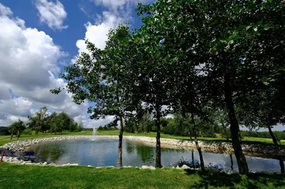 a pond with trees in the middle of a field at Stay at Royal Kraków Golf