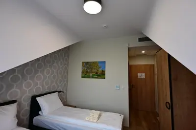 a small bedroom with a bed and a staircase at Stay at Royal Kraków Golf