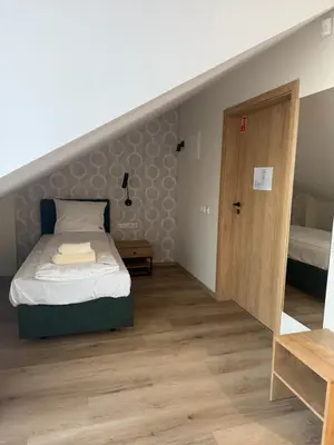 a small bedroom with a bed and a wooden floor at Stay at Royal Kraków Golf