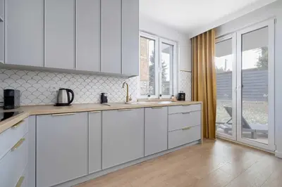 a kitchen with white cabinets and a large window at Modern Apartment Kraków Potrzask - AC, Terrace & Parking by Noclegi Renters in Kraków