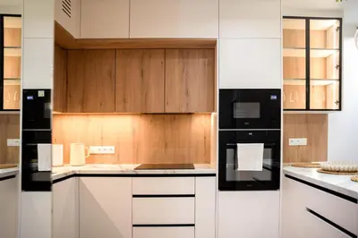 a kitchen with white cabinets and black appliances at Apartament Zakrzówek - Chilloway in Kraków