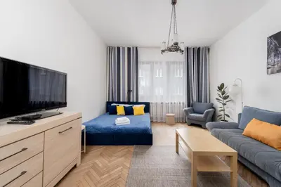 a living room with a blue couch and a tv at Urzędnicza Homely Apartment by BookingHost in Kraków
