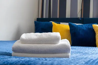 a stack of towels sitting on top of a bed at Urzędnicza Homely Apartment by BookingHost in Kraków