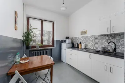 a kitchen with white cabinets and a wooden table at Urzędnicza Homely Apartment by BookingHost in Kraków