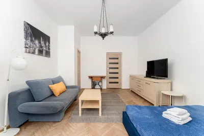 a living room with a blue couch and a tv at Urzędnicza Homely Apartment by BookingHost in Kraków