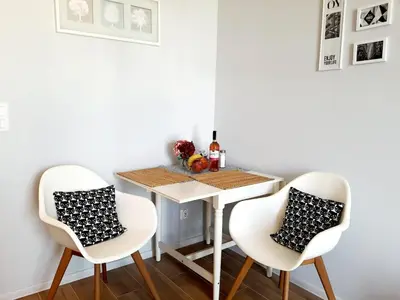 a dining room table with two white chairs and a table with at Modern studio on Wrocławska with balcony in Kraków