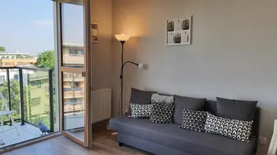 a living room with a gray couch with pillows at Modern studio on Wrocławska with balcony in Kraków