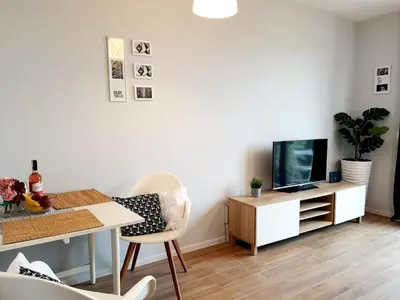 a living room with a table and a tv and a desk at Modern studio on Wrocławska with balcony in Kraków