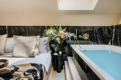 a hotel room with a tub and a bed and flowers at The Krakow Palace near Wawel Castle by BQQK in Kraków