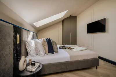 a bedroom with a bed with a tv on the wall at The Krakow Palace near Wawel Castle by BQQK in Kraków