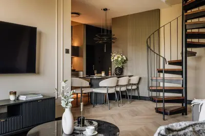 a living room with a staircase and a table with chairs at The Krakow Palace near Wawel Castle by BQQK in Kraków