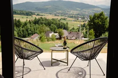 a table with a bottle of wine sitting between two chairs at Vidok House