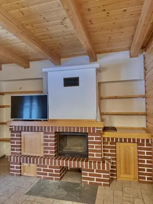 a living room with a brick fireplace with a flat screen tv at Leśna Przystań in Sidzina