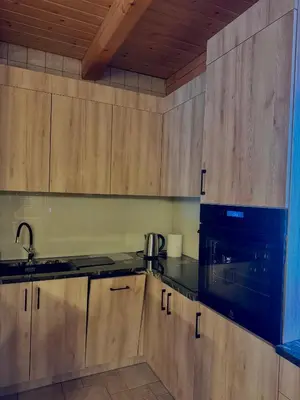 a kitchen with wooden cabinets and a black stove top oven at Leśna Przystań in Sidzina