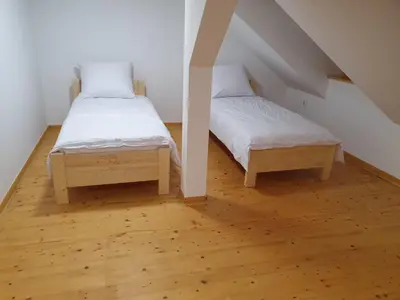 two beds in a room with wooden floors at Leśna Przystań in Sidzina