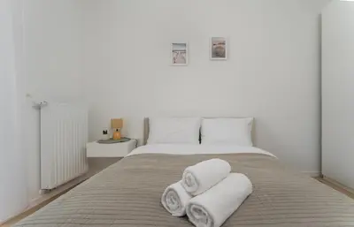 a white bedroom with a bed with towels on it at Czerwone Maki Deluxe Apartment by BookingHost in Kraków