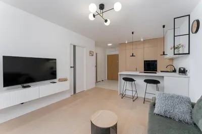 a living room and kitchen with a flat screen tv at Czerwone Maki Deluxe Apartment by BookingHost in Kraków