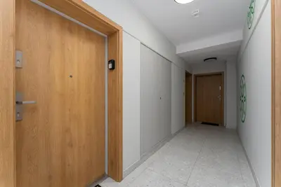 an empty hallway with wooden doors and a tile floor at Czerwone Maki Deluxe Apartment by BookingHost in Kraków