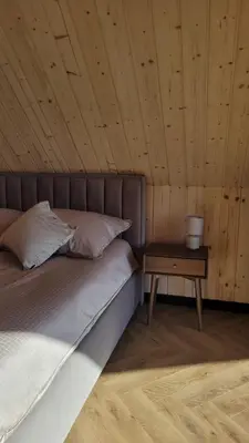 a bed in a wooden room with a night stand at Stodoła na Hamajdówce in Zubrzyca Górna