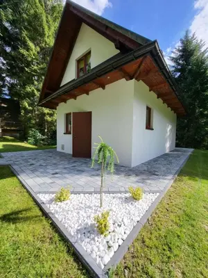 a small white house with a palm tree in the yard at Ośrodek Nad Potokiem in Poręba Wielka