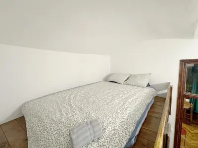 a bed in a room with a white wall at Tawerna Krakowska in Kraków