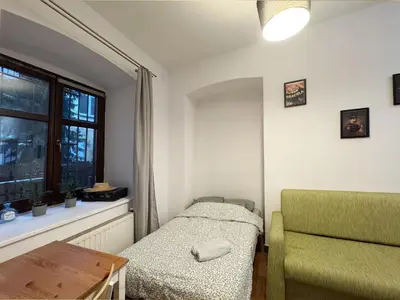 a bedroom with a bed and a chair and a window at Asnyka comfy in Kraków