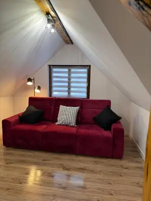a red couch in a room with a attic at Domek Ostoja Zator Graboszyce in Graboszyce