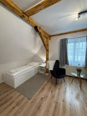 a bedroom with a bed and a chair and a table at Domek Ostoja Zator Graboszyce in Graboszyce