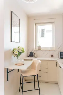 a white kitchen with a table and a vase of flowers at Tauron Arena - Parking, Balcony, AirCon - by Rentujemy in Kraków
