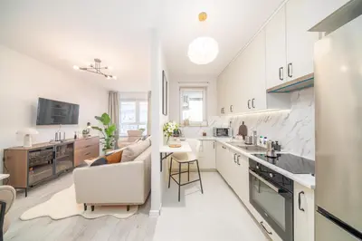 a kitchen and living room with white cabinets at Tauron Arena - Parking, Balcony, AirCon - by Rentujemy in Kraków