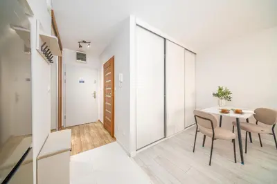 a dining room with white walls and a table and chairs at Tauron Arena - Parking, Balcony, AirCon - by Rentujemy in Kraków