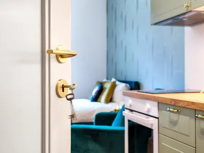 a blue kitchen with a bed in the background at Quiet Courtyard Studio by Tyzenhauz in Kraków