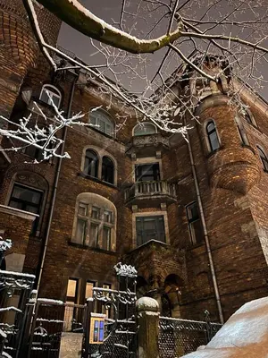 an old brick building with snow on the branches of a tree at Modern studio Old Town Railway Station in Kraków