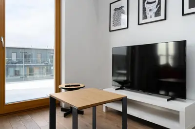 a living room with a table and a large tv at Bulwar Kurlandzki Downtown Apartment by BookingHost in Kraków